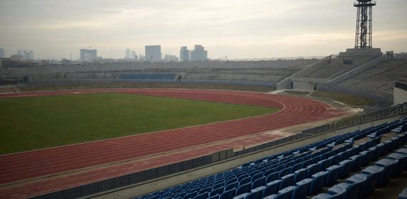 Estadio de atletismo vacío con el pebetero apagado sobre la grada al atardecer