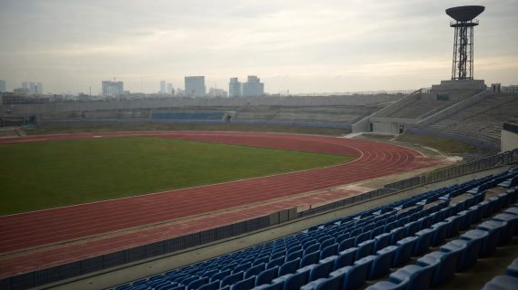 Estadio de atletismo vacío con el pebetero apagado sobre la grada al atardecer