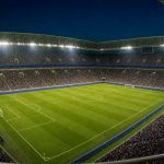 Estadio de fútbol lleno con los focos encendidos y el césped recién marcado antes de una jornada inaugural