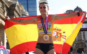 María Pérez despliega la bandera de España con la medalla al cuello y una corona en la cabeza tras ganar el medio maratón marcha