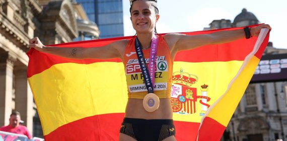 María Pérez despliega la bandera de España con la medalla al cuello y una corona en la cabeza tras ganar el medio maratón marcha