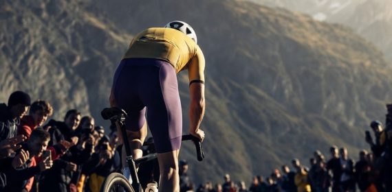 Ciclista de espaldas atacando en la subida a un puerto de montaña entre el público