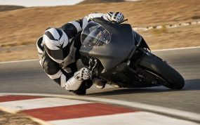 Una moto de competición inclinada al límite con la rodilla del piloto rozando el asfalto en la salida de una curva