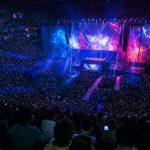 Público llenando un pabellón durante una final de esports, con las pantallas del escenario iluminadas