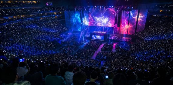 Público llenando un pabellón durante una final de esports, con las pantallas del escenario iluminadas