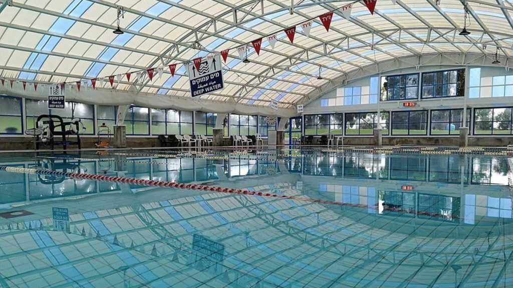 Una piscina cubierta vacía bajo una cubierta acristalada, con las corcheras puestas