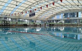 Una piscina cubierta vacía bajo una cubierta acristalada, con las corcheras puestas
