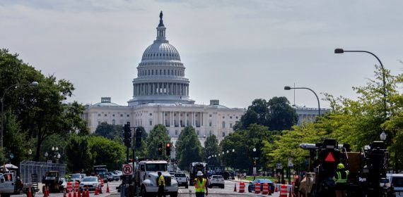 Operarios y maquinaria asfaltan una avenida de Washington con el Capitolio al fondo