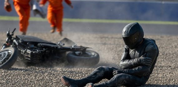 Un piloto sentado en la grava se sujeta el hombro tras una caída mientras los comisarios acuden hacia él