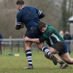 Un jugador de rugby amateur placa a la altura de la cintura con la cabeza a un lado en un campo municipal