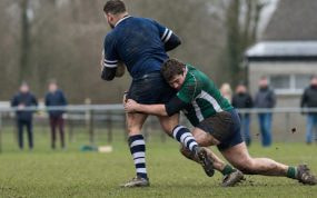 Un jugador de rugby amateur placa a la altura de la cintura con la cabeza a un lado en un campo municipal