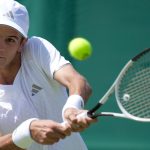 Rafa Jódar golpea un revés a dos manos vestido de blanco durante un partido sobre hierba