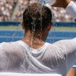 Un tenista se echa agua helada sobre la nuca en el banquillo durante un cambio de lado en pista dura