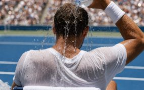 Un tenista se echa agua helada sobre la nuca en el banquillo durante un cambio de lado en pista dura