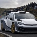 Coche de rally de la máxima categoría saliendo de una horquilla de asfalto en una carretera de montaña con público en las cunetas