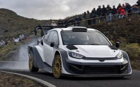 Coche de rally de la máxima categoría saliendo de una horquilla de asfalto en una carretera de montaña con público en las cunetas