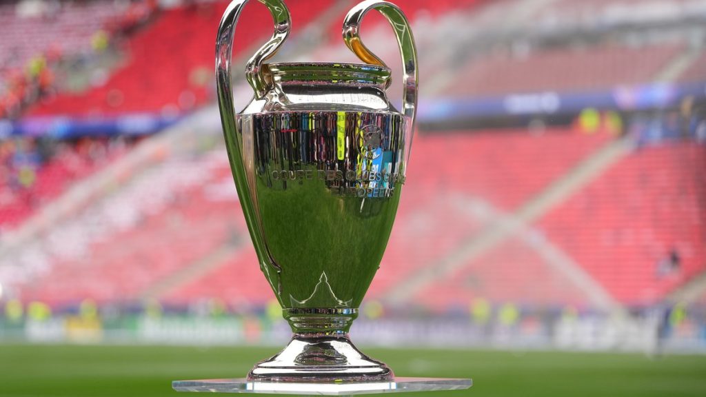 El trofeo de la Liga de Campeones sobre una peana de metacrilato en el césped de un estadio