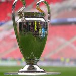 El trofeo de la Liga de Campeones sobre una peana de metacrilato en el césped de un estadio
