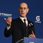 Adam Silver gesticula con la mano derecha tras el atril durante una rueda de prensa, con el panel azul de la NBA al fondo