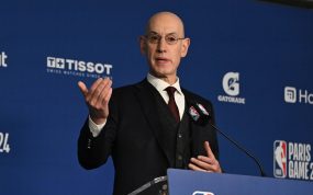 Adam Silver gesticula con la mano derecha tras el atril durante una rueda de prensa, con el panel azul de la NBA al fondo