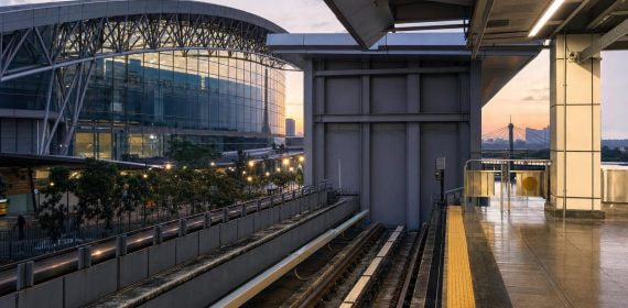 Andén vacío de una estación de metro moderna junto a un recinto ferial al anochecer