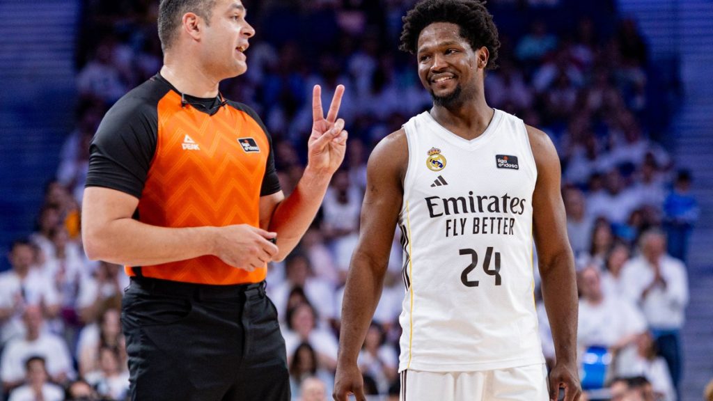 El árbitro Arnau Padrós, con camiseta naranja, hace un gesto con dos dedos junto a Andrés Feliz, del Real Madrid