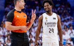 El árbitro Arnau Padrós, con camiseta naranja, hace un gesto con dos dedos junto a Andrés Feliz, del Real Madrid