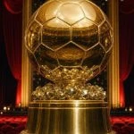Trofeo dorado con forma de balón sobre un pedestal en el escenario de un teatro con cortinas de terciopelo rojo