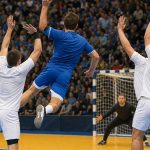 Un lateral salta para lanzar a portería ante el bloqueo de dos defensores en un partido de balonmano