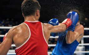 Un boxeador de rojo, de espaldas, conecta un directo a su rival de azul, que se cubre en un ring de competición