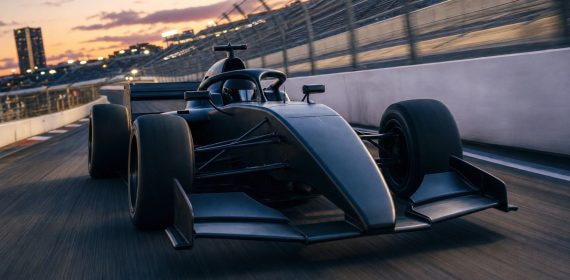 Monoplaza de Fórmula 1 sin decoración rodando en un circuito urbano al atardecer