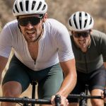 Tres ciclistas atacan de frente una rampa en una carretera de sierra bajo el sol