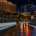 Circuito urbano nocturno entre hoteles con el asfalto húmedo reflejando las luces
