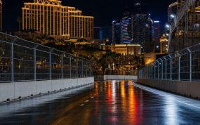Circuito urbano nocturno entre hoteles con el asfalto húmedo reflejando las luces