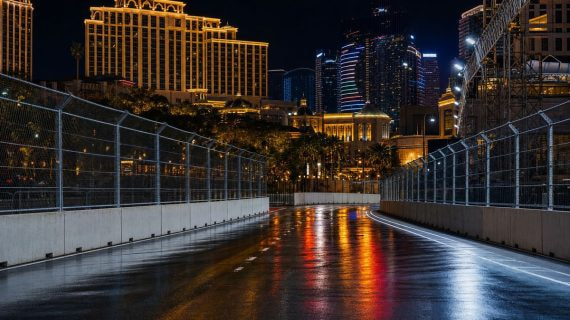 Circuito urbano nocturno entre hoteles con el asfalto húmedo reflejando las luces