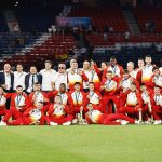 Los jugadores y el cuerpo técnico de la selección española posan con las medallas de oro sobre el césped de un estadio