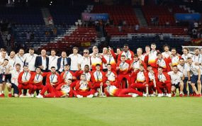 Los jugadores y el cuerpo técnico de la selección española posan con las medallas de oro sobre el césped de un estadio