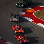 El Ferrari 499P rojo número 50 persigue a un grupo de prototipos por una curva con pianos rojos y blancos