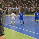 Una cámara de televisión enfoca una jugada de fútbol sala en un pabellón con las gradas llenas