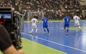 Una cámara de televisión enfoca una jugada de fútbol sala en un pabellón con las gradas llenas