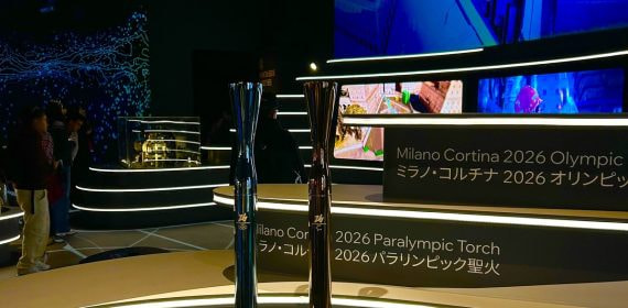 Las antorchas olímpica y paralímpica de Milano-Cortina 2026, sobre una peana iluminada junto a los rótulos del evento