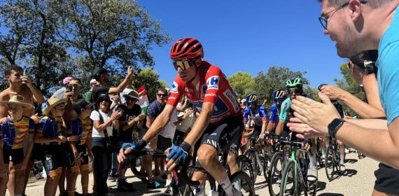 Enric Mas asciende con el maillot rojo de líder entre el público durante La Vuelta a España 2026