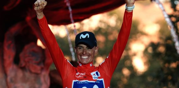 Enric Mas levanta los dos puños con el maillot rojo en el podio de Granada