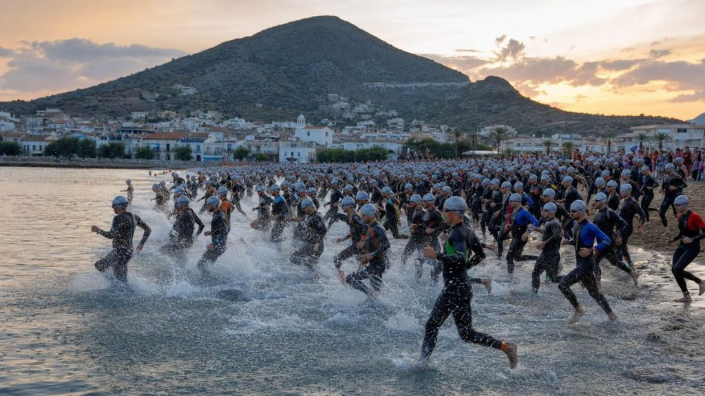 Cientos de triatletas con neopreno entrando al mar Mediterráneo al amanecer desde una playa ancha