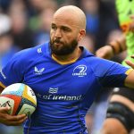 Jamison Gibson-Park corre con el balón bajo el brazo y la camiseta azul del Leinster Rugby mientras aparta a un rival