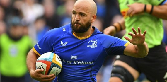 Jamison Gibson-Park corre con el balón bajo el brazo y la camiseta azul del Leinster Rugby mientras aparta a un rival