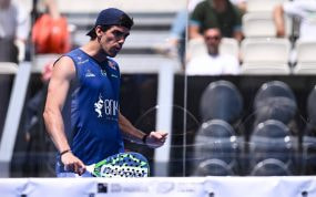 Juan Lebrón, con gorra y camiseta azul, aprieta el puño con la pala en la mano junto a la red de una pista de pádel