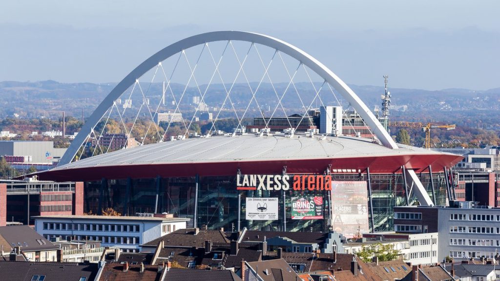 Vista exterior del Lanxess Arena de Colonia con su arco blanco sobre los tejados de la ciudad