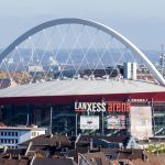 Vista exterior del Lanxess Arena de Colonia con su arco blanco sobre los tejados de la ciudad