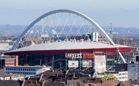 Vista exterior del Lanxess Arena de Colonia con su arco blanco sobre los tejados de la ciudad